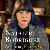 photo of author's book cover: author sitting at a table in front of a bookcase