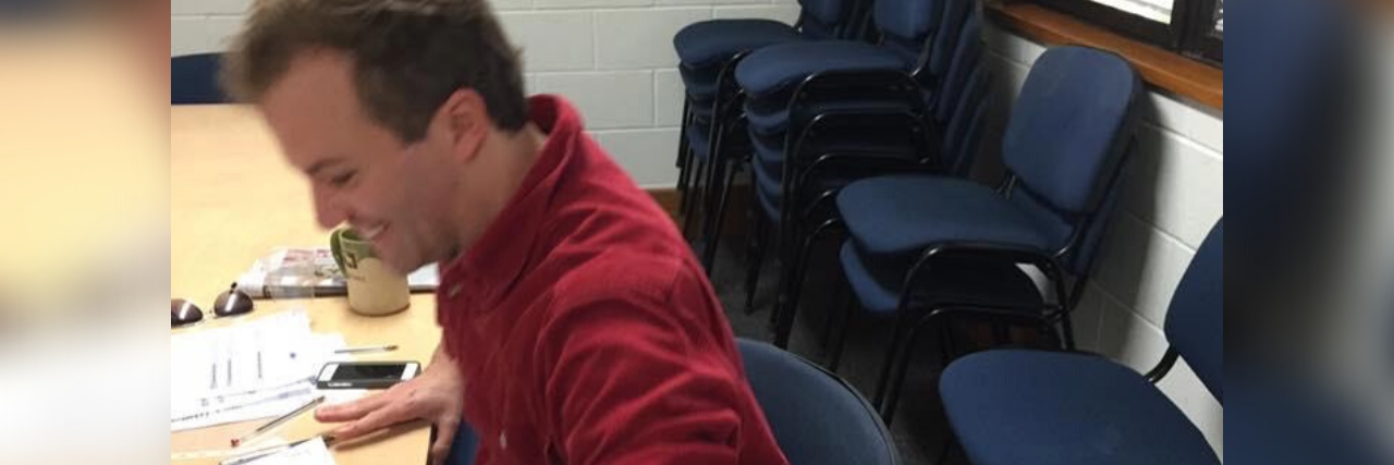 Borderline Personality Disorder Makes Me Feel Defeated Before Starting photo of author in a red shirt sitting at a desk smiling