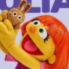 Muppet Julia from Sesame Street holding up a fuzzy bunny