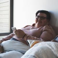 Woman in bed using smartphone.