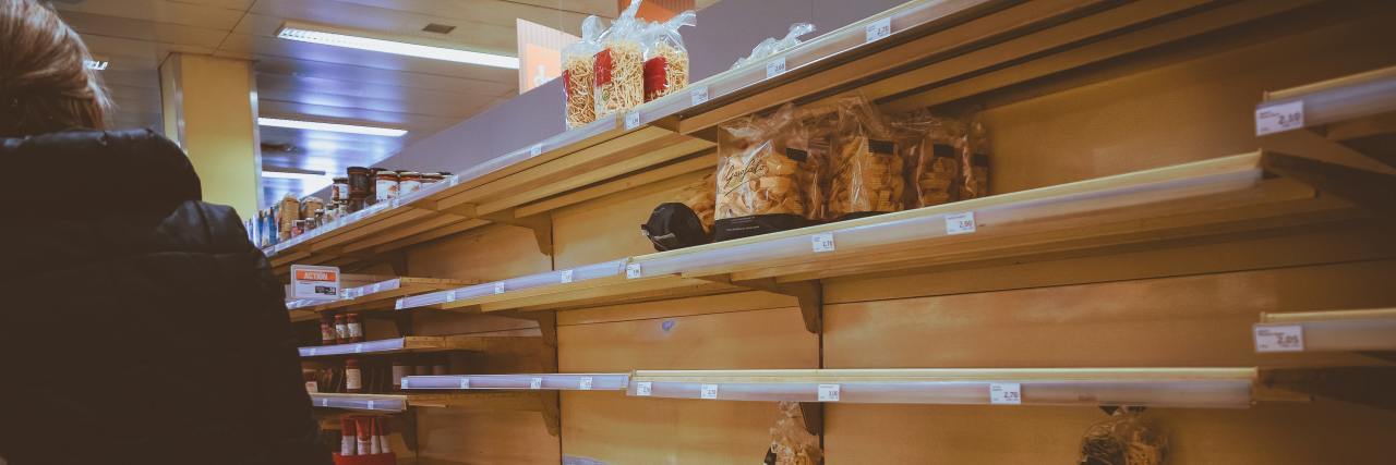 My Experience With Psychosis Shows We Shouldn't Panic Buy for COVID-19 person shopping in an aisle with empty shelves