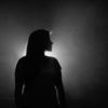 black and white photo of woman silhouetted against white light in profile view