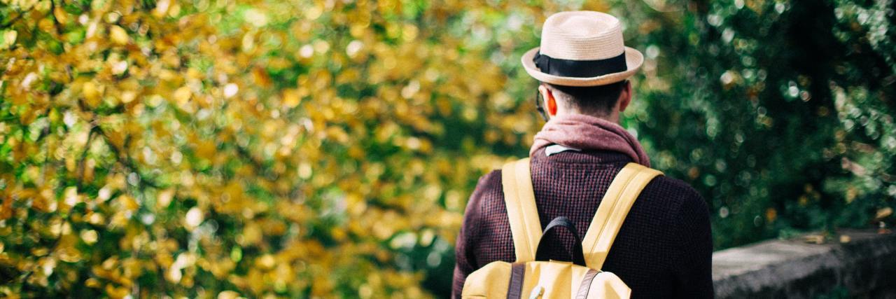 Feeling Defective Because of Childhood Trauma and Addiction photo of man in hat and yellow backpack standing on bridge with trees