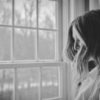black and white photo of a woman looking out the window
