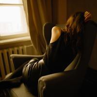 back of a woman stressed in black curled up in a chair