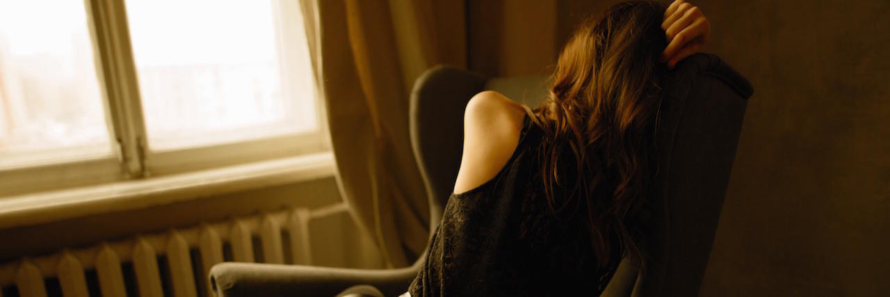 The Reality of Living With Lyme Disease Woman sitting in a chair, facing away from the camera