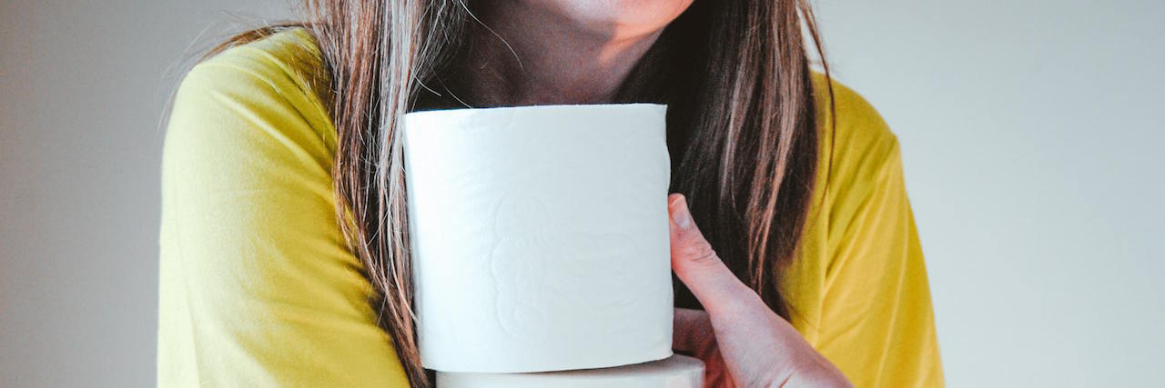 A woman holding rolls of toilet paper