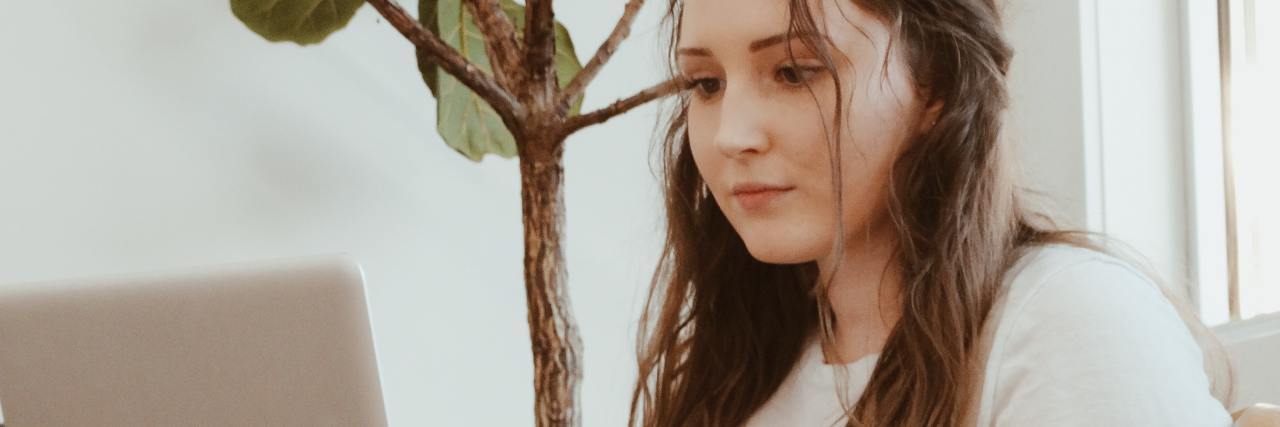 Social Media Helped My Mental Health When I Couldn't Leave the House photo of young woman on couch with laptop on her knee