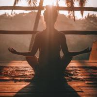 photo of woman practicing yoga or meditating on balcony at sunset
