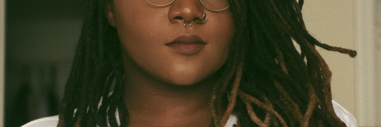 How the Adoption Industry Causes Trauma for Transracial Adoptees Black woman with long locks wearing a white T-shirt and crossing her arms