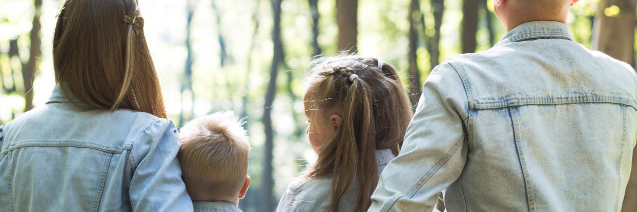 We Need to Prepare (Not Panic) Our Kids When it Comes to COVID-19 photo of family sitting together in woods, with parents and two young children