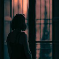photo of woman silhouetted in front of window with orange light