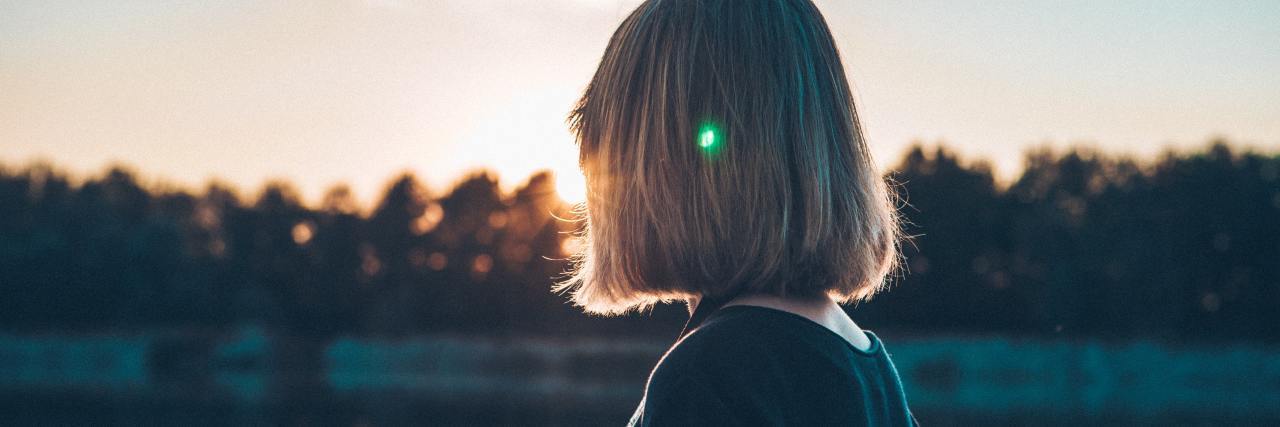 I Was Surprised When My Therapist Mentioned Emotional Trauma photo of young woman near lake at sunset with silhouetted trees and reflections in background