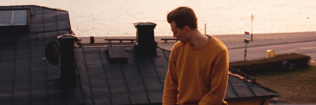 What to Do When People Think Your Depression Isn't Real photo of man sitting on metal railing over city at sunset