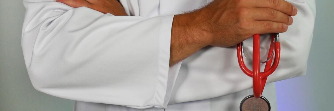 Dr. Victor Tapson Shares How COVID-19 May Impact PAH Patients Doctor in a white lab coat, arms only, holding a red stethoscope