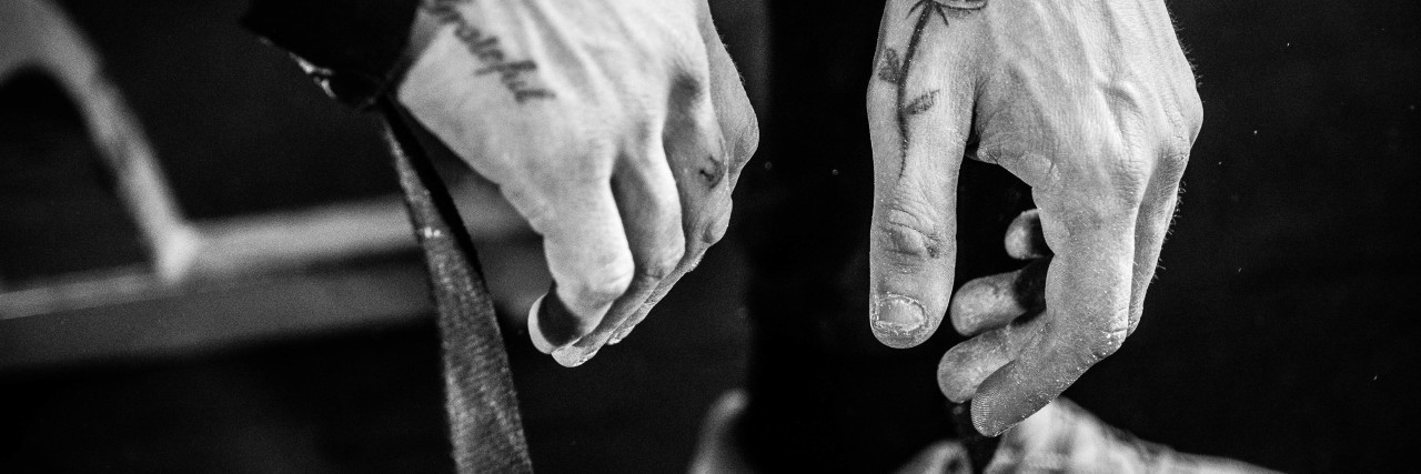 monochrome image of man's tattooed hands with sweatbands