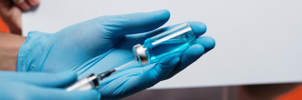 Why People Should Still Be Able to Get Allergy Shots During COVID-19 A health care worker fills a syringe from a vial in front of a sign that says COVID-19