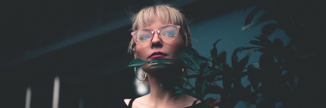 How Second Chances Saved Me From Suicide During My Darkest Months woman in a striped shirt with glasses standing in front of a plant looking out