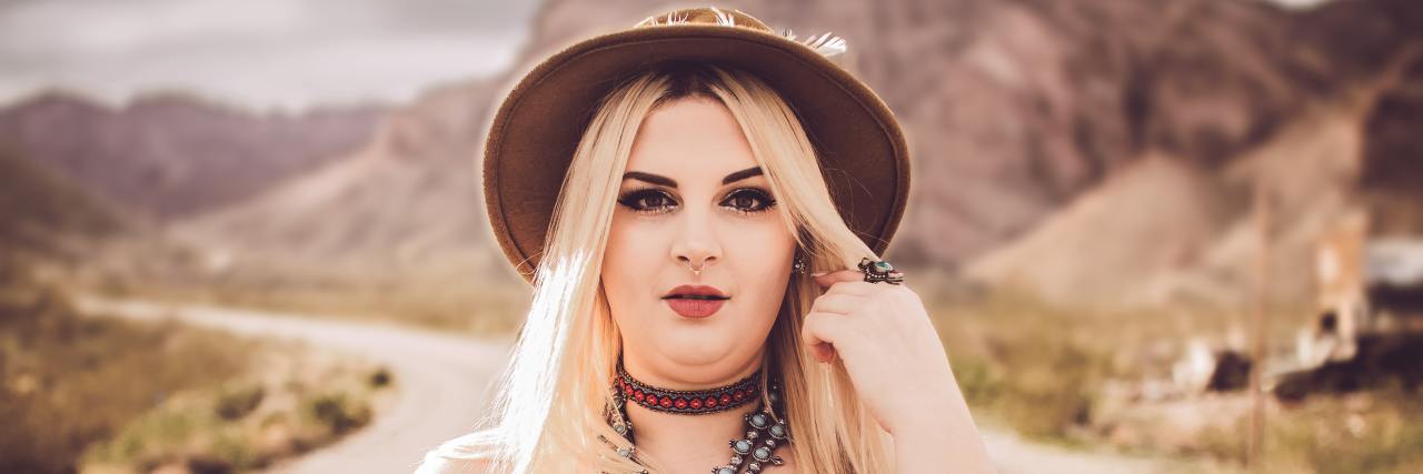How I Found Hope While Trying to Die by Suicide Due to Bullying woman in a hat standing in a dirt rode with an American flag top on