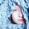 A woman hiding under a blue blanket, just her head peaking out