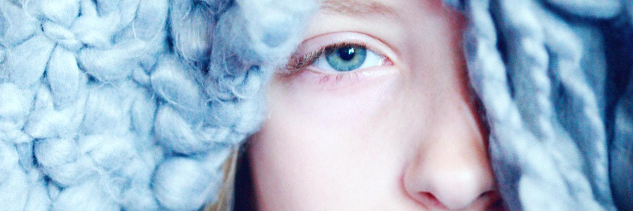 Tips for Managing Borderline Personality Disorder in COVID-19 Pandemic A woman hiding under a blue blanket, just her head peaking out