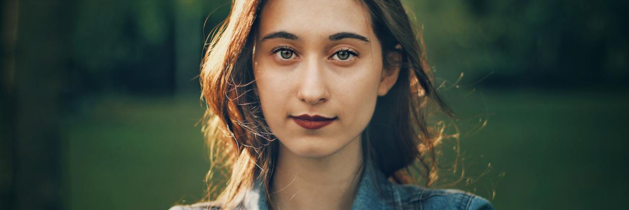 Using Anxiety Coping Strategies to Help With COVID-19 photo of young woman with dark hair, wearing denim jacket, looking to camera with subtle smile