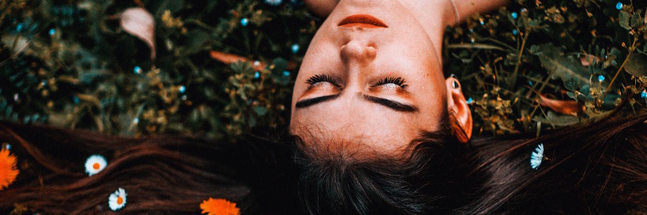 Figuring Out How to Live Without an Eating Disorder A woman laying on the ground with flowers in her hair