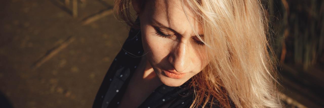 photo of blonde woman in sunlight with eyes closed, looking down