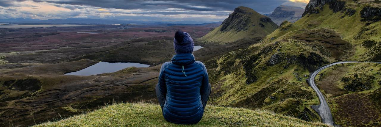 I Feel Like My Mental Health Isn't Getting Better or Worse photo of woman sitting on grass on top of mountain with mountains and sunset in distance