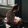 photo of woman sitting in sunlight reading a book