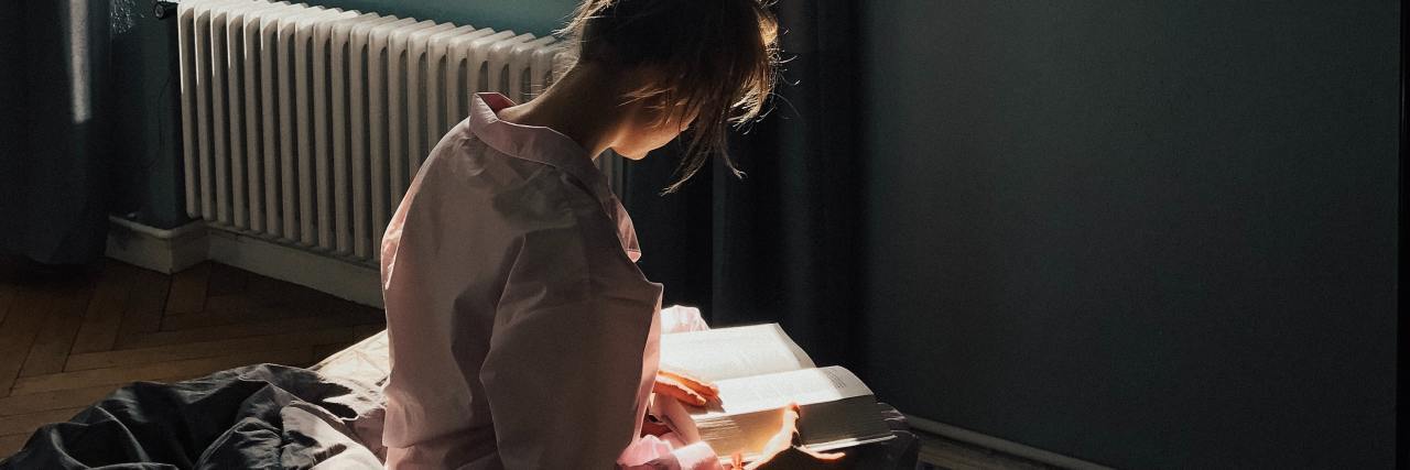 Tips for Passing Time While Self-Isolating With Coronavirus photo of woman sitting in sunlight reading a book