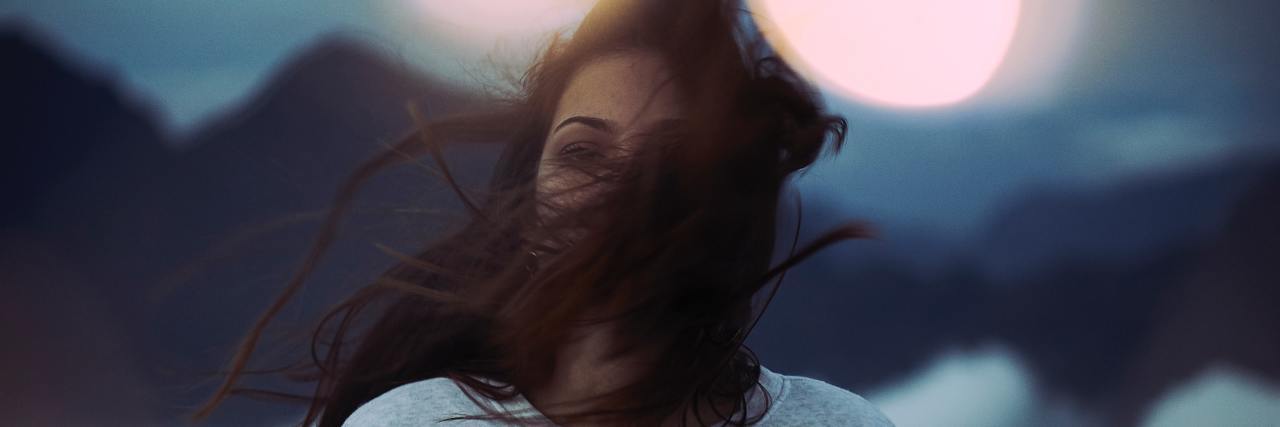 6 'Weird' Ways I Experience Anxiety That Don't Fit the Stereotype woman standing with her brown hair blowing across her face