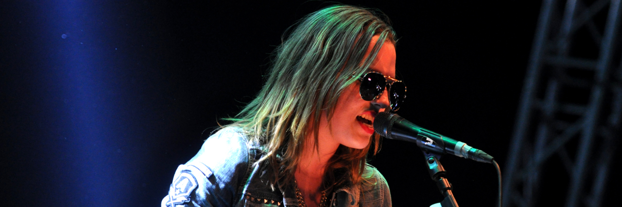 Lzzy Hale's #RaiseYourHorns Campaign Promotes Mental Health Awareness Lzzy Hale performs onstage with her guitar.