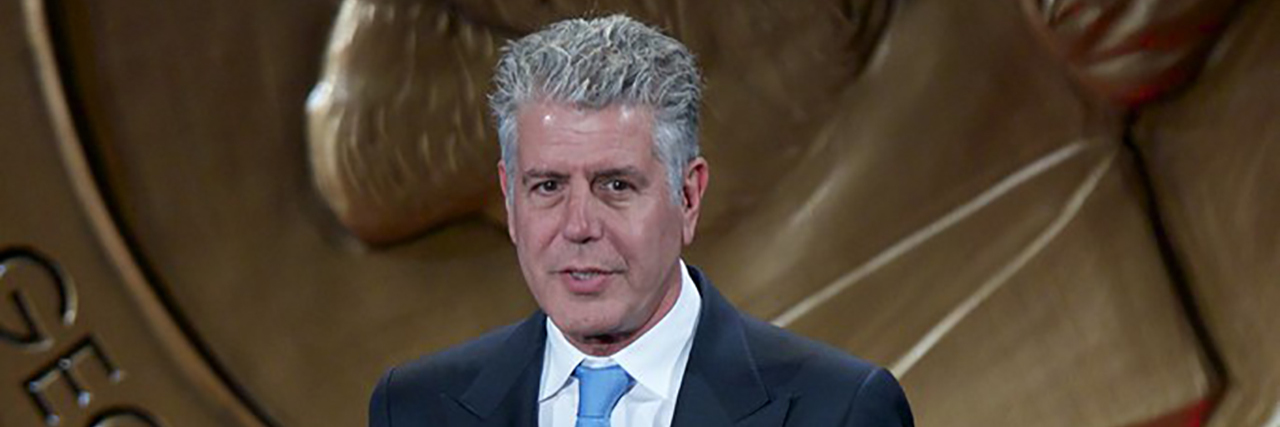 Anthony Bourdain accepts an award in a suit