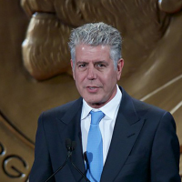 Anthony Bourdain accepts an award in a suit