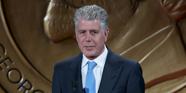 Anthony Bourdain accepts an award in a suit