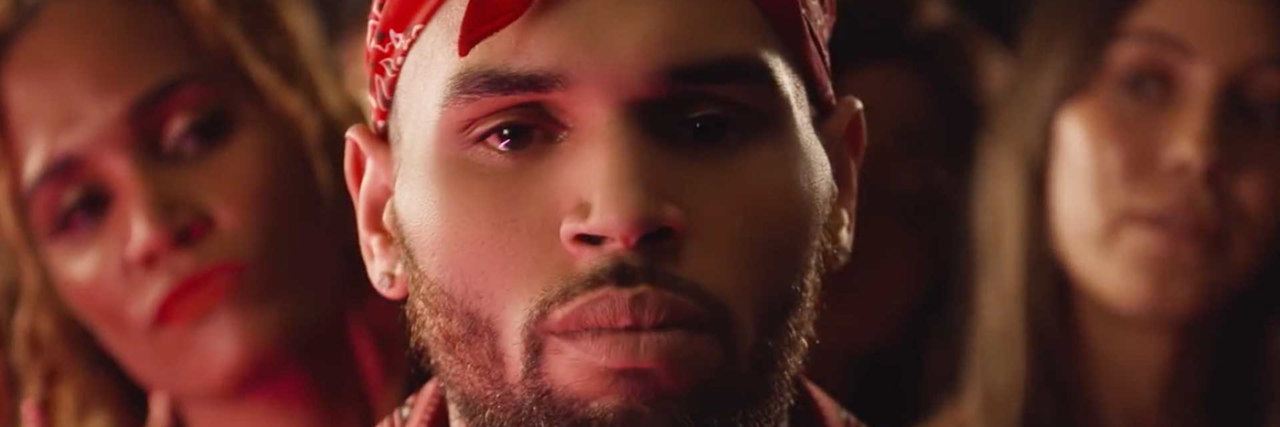 A headshot of Chris Brown, who is wearing a red outfit