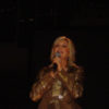 Olivia Newton-John performs onstage in a gold ensemble