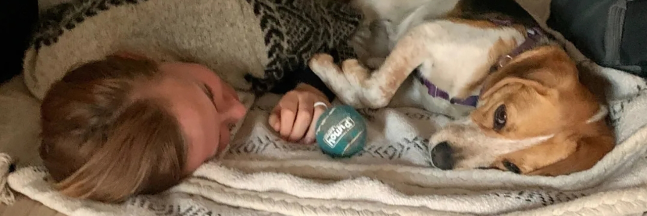 Living in a Van During a Chronic Illness Flare Chelsea in bed during a chronic illness flare cuddling with her dog.