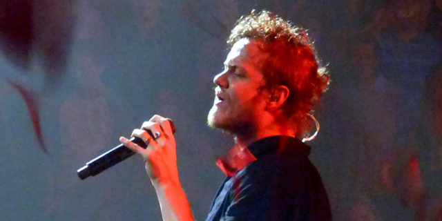 Dan Reynolds sings onstage while wearing a blue or black outfit