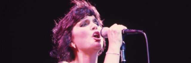 An older photo of Linda Ronstadt singing onstage with her band