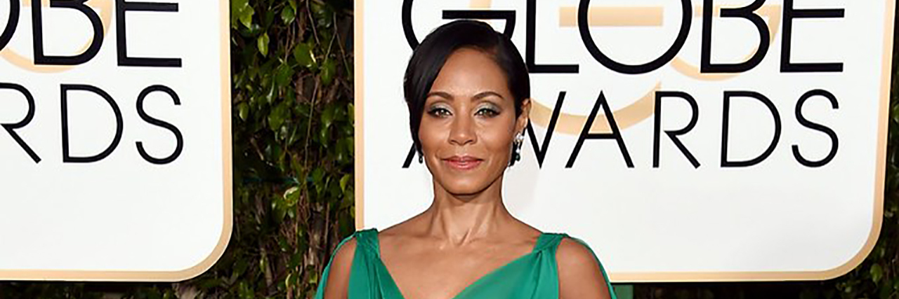 Jada Pinckett Smith poses in a green gown on the Golden Globes red carpet