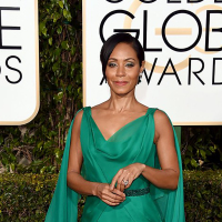 Jada Pinckett Smith poses in a green gown on the Golden Globes red carpet