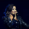 Demi Lovato sings onstage while wearing a black outfit