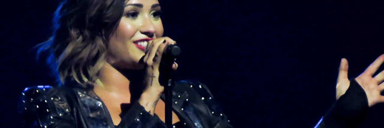 Demi Lovato sings onstage while wearing a black outfit