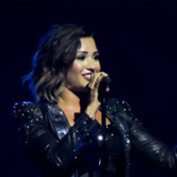 Demi Lovato sings onstage while wearing a black outfit