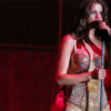 Selena Gomez singing onstage while wearing a gold costume