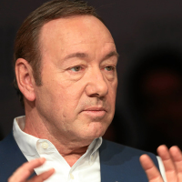 Kevin Spacey raises his hands defensively while talking to a moderator on panel