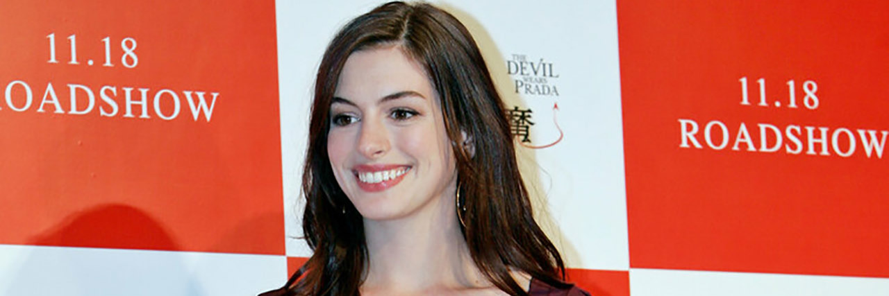 Anne Hathaway poses for the red carpet in a maroon dress