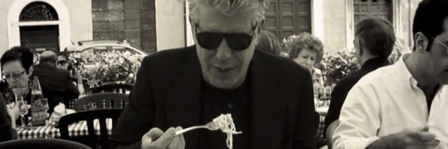 A black and white photo of Anthony Bourdain eating pasta